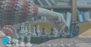 Section of a chess board with a player moving a white piece into a new position. An Every Compliance By IRIS gradient overlays the image.